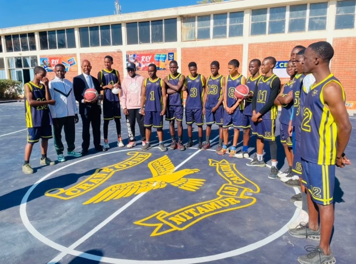 The basketball team gathered around the school crest on the court
