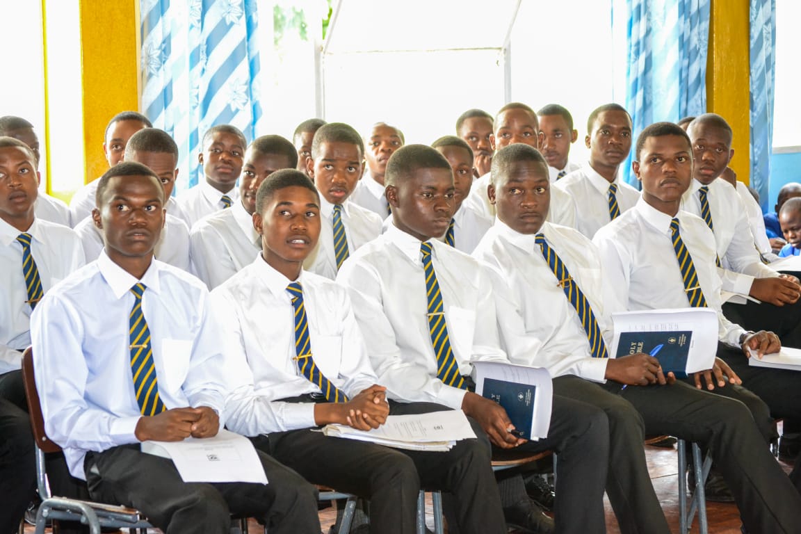 Students seated in white shirts and school ties